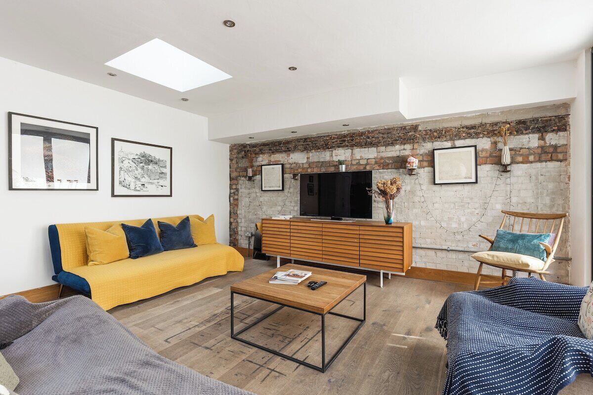A living room with a sofa, coffee table, and a television against a brick wall.