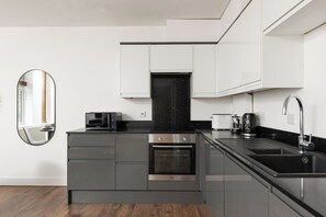 A modern kitchen with a built-in oven, a microwave, and a coffee maker. - New! Delightful 2BR | 1 Min to Lower Sydenham (London)