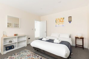 A bedroom with a bed, a bedside table, a nightstand, a mirror, and a wall-mounted artwork. - New! Spacious 3BR | Garden & Parking | Willesden (Greater London)
