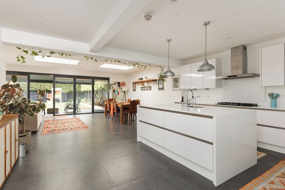 A modern kitchen with a central island, pendant lighting, and a view to the outside.