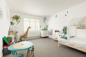 A child's room with a bed, a play table, a dresser, and wall decorations including a giraffe and a zebra. - New! Spacious 3BR | Garden & Parking | Willesden (Greater London)