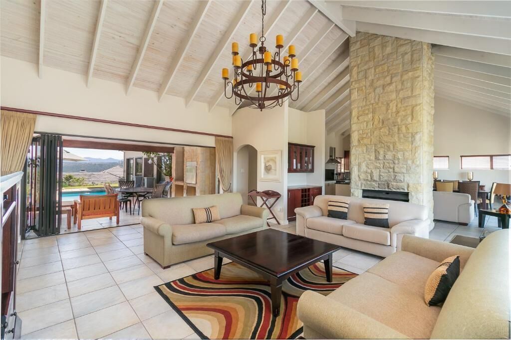 A spacious living area with a large chandelier, a stone accent wall, and a view of the outdoors.