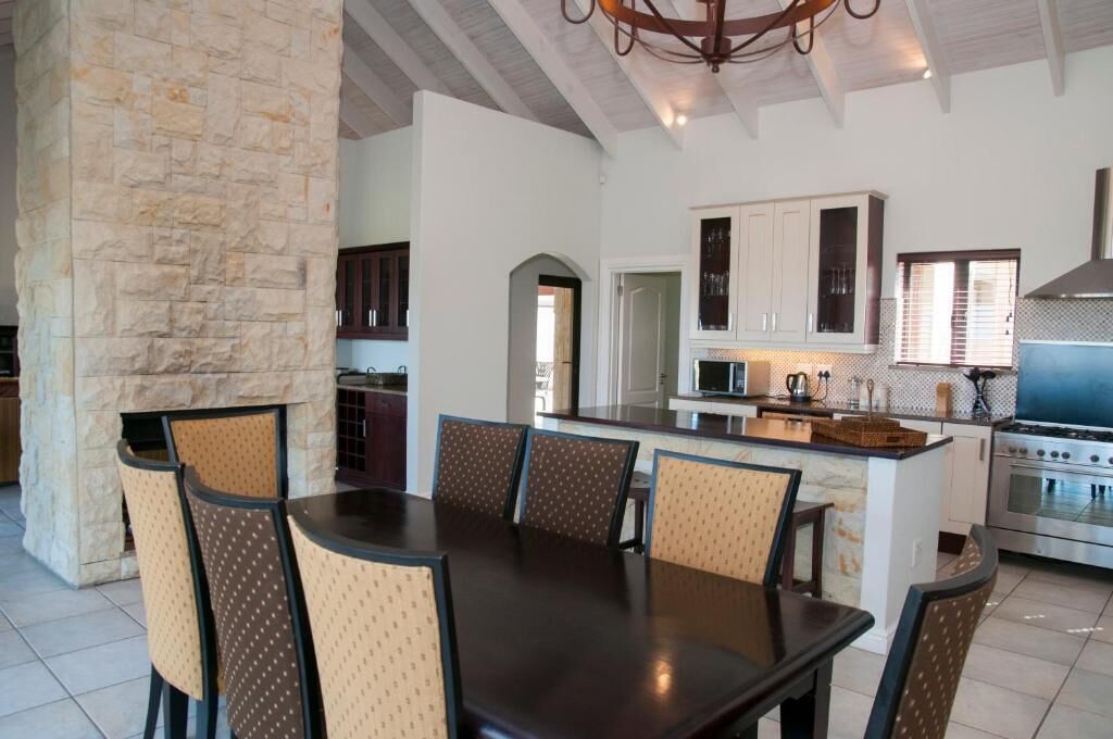 A modern kitchen with white cabinets, a built-in oven, and a dining area with a large table and chairs.