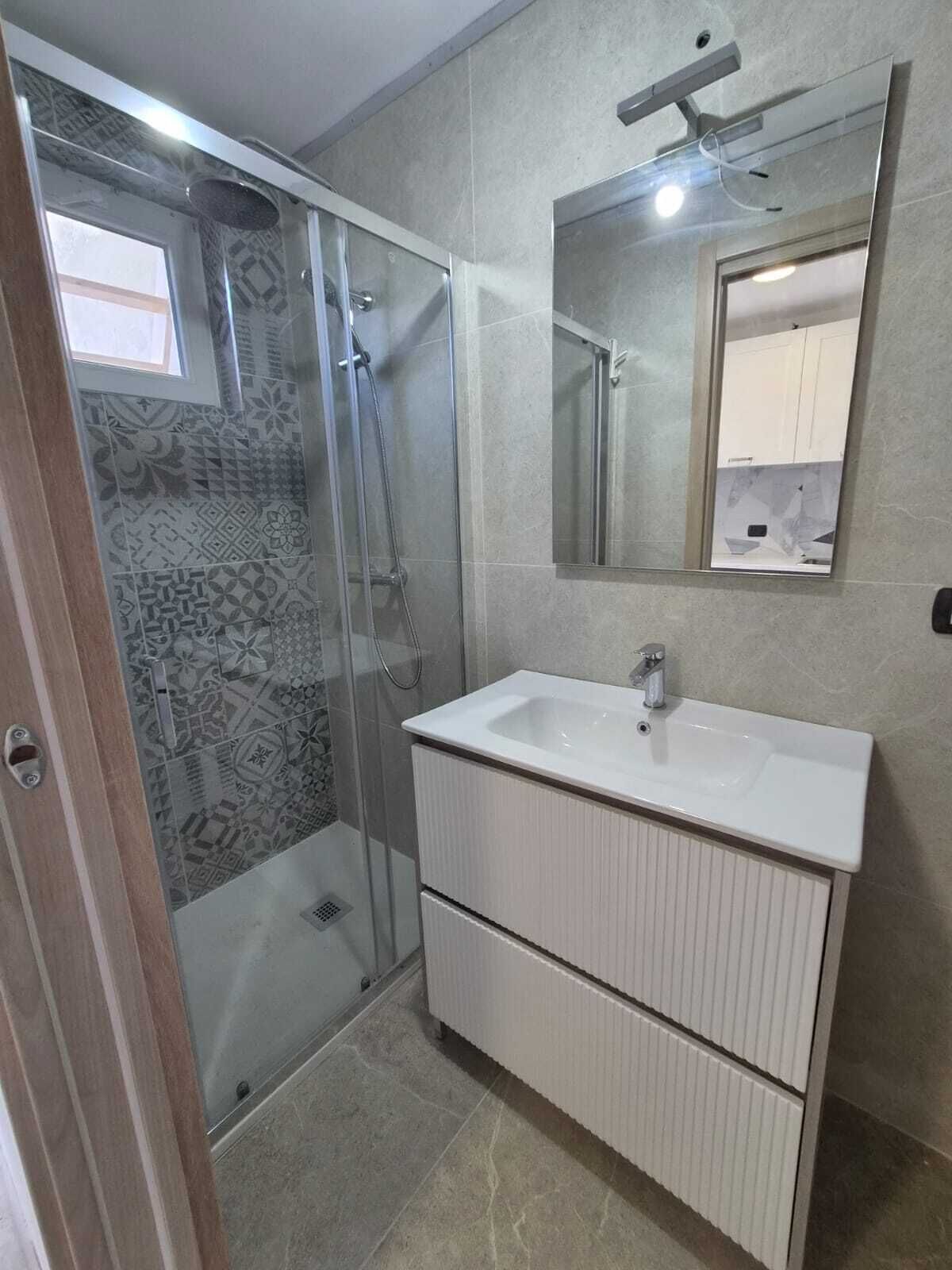 Ein Badezimmer mit Dusche, Waschbecken und Spiegel.
