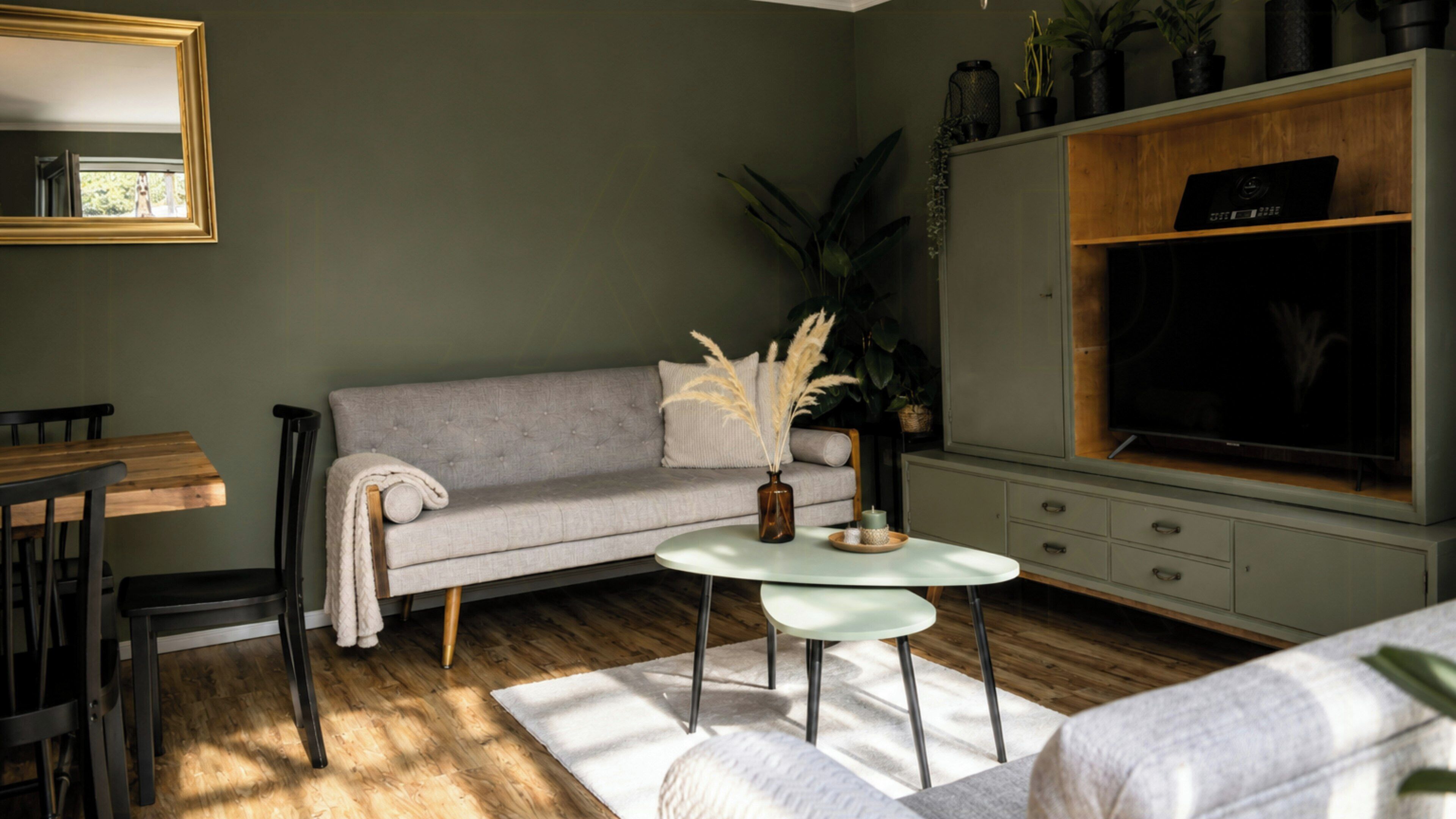 Un salon avec un canapé gris, une table basse, un téléviseur et un plancher en bois.