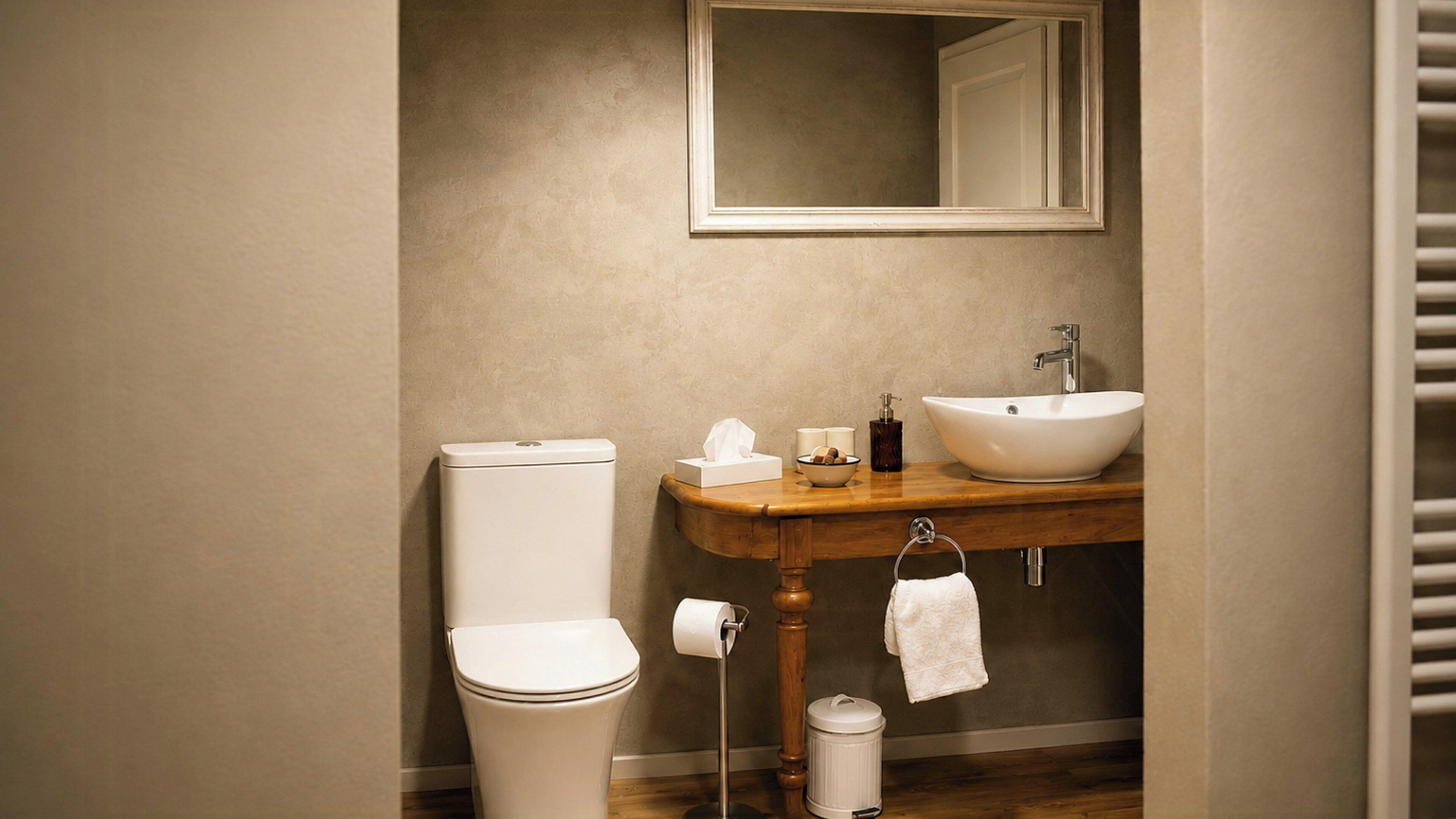 Une salle de bain équipée de toilettes, d’un lavabo, d’un miroir et d’un meuble-lavabo en bois.