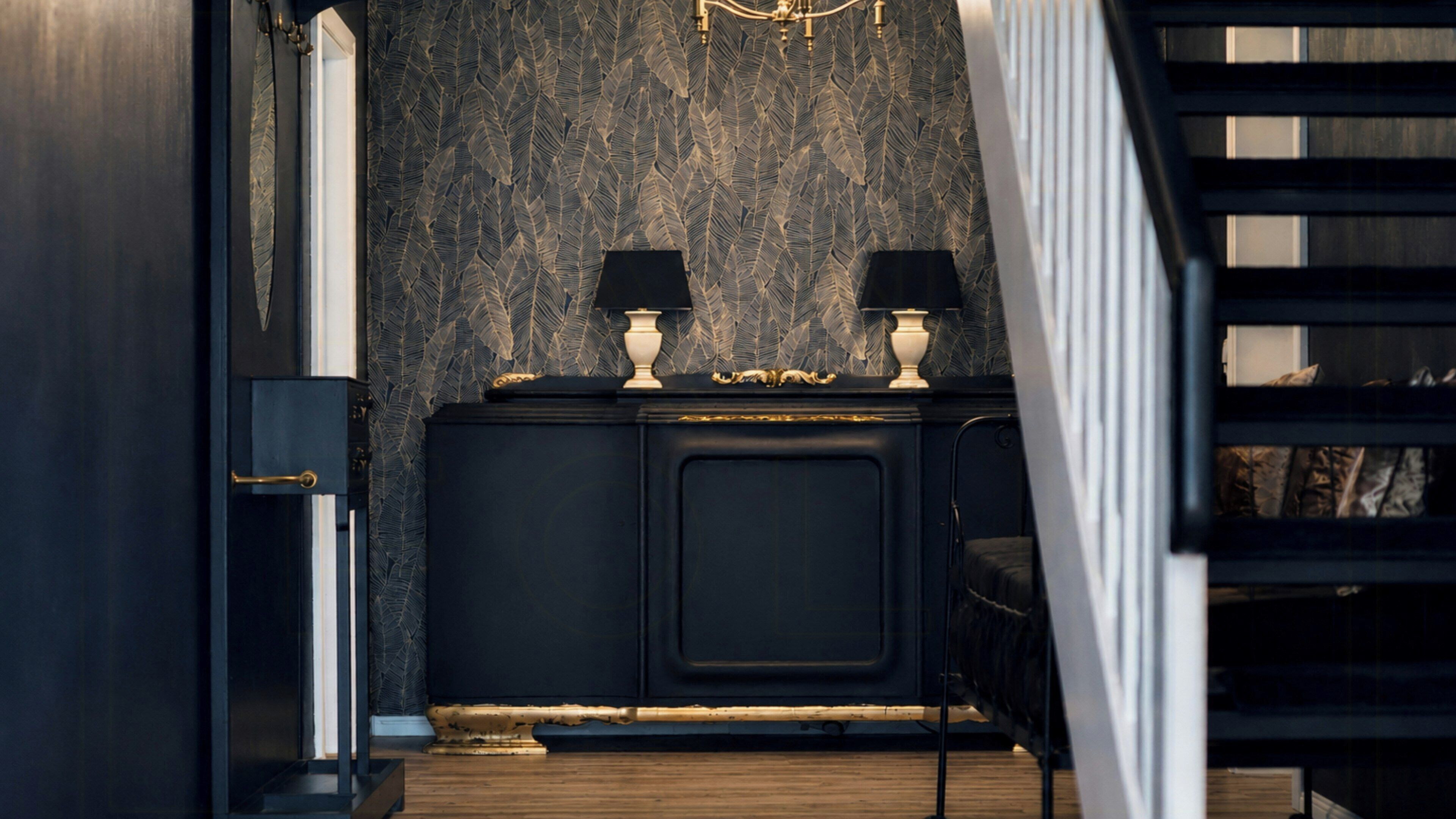 A dark wood cabinet with two lamps, a patterned wall, and a staircase.