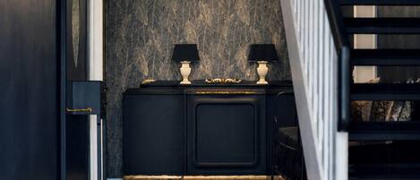 A dark wood cabinet with two lamps, a patterned wall, and a staircase.