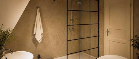 Une salle de bain moderne équipée d’une baignoire, d’une douche à parois de verre, d’un lavabo et d’un porte-serviettes.