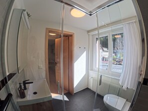 Un bagno moderno con cabina doccia in vetro, un lavandino e un water.