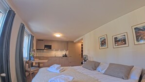 A hotel room with a bed, a desk, and a kitchenette. - 1628 Aurora Studio ohne Balkon by Interhome (Lenzerheide)