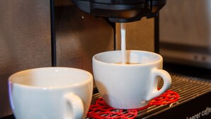 A coffee machine dispensing coffee into two white cups on a tray. - 1628 Aurora Studio ohne Balkon by Interhome (Lenzerheide)