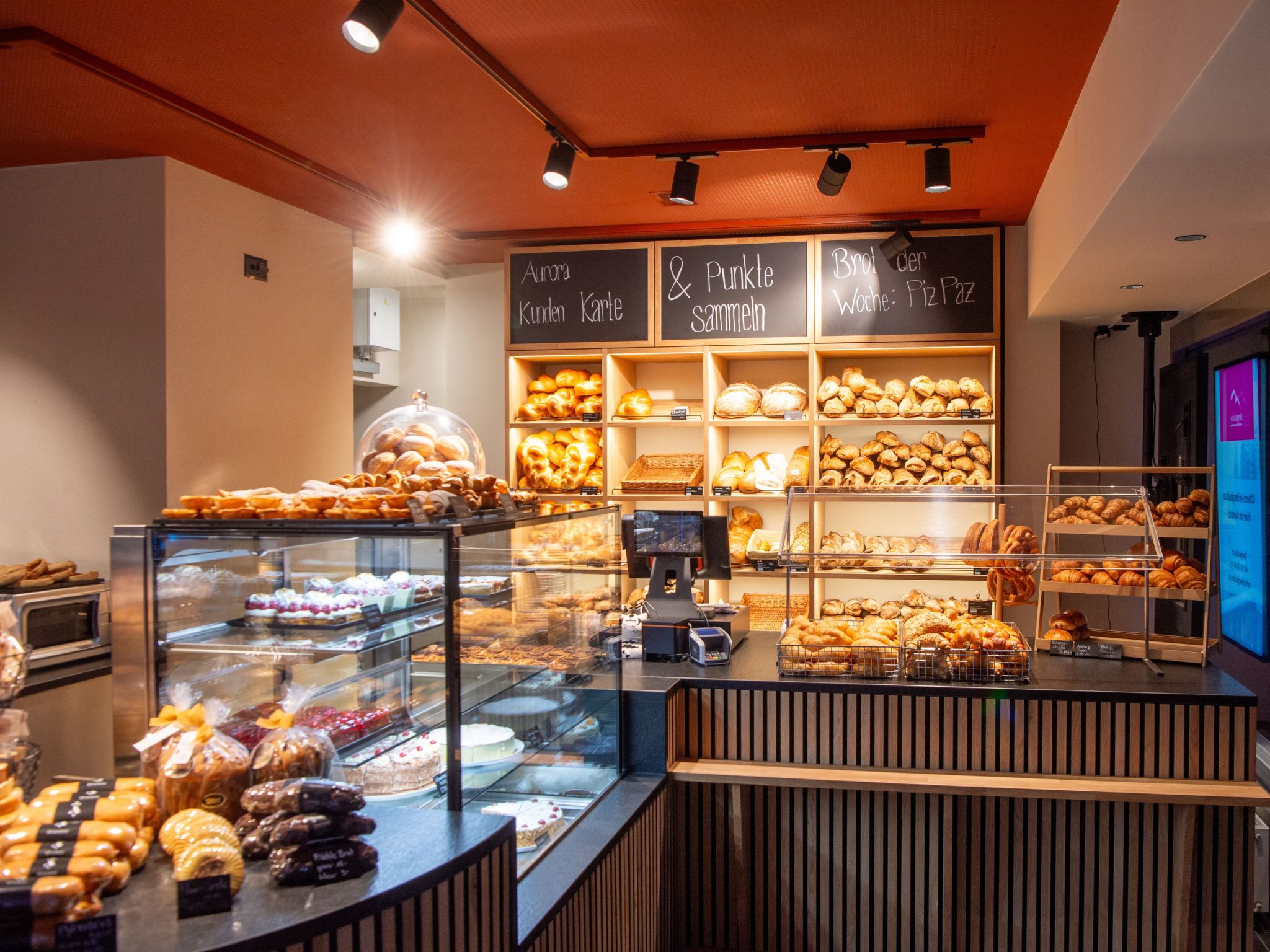 Mostrador de una panadería con diversos productos horneados y una caja registradora.