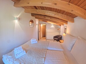 Ein Schlafzimmer mit einem Bett, einem Sessel, einem Spiegel und einer Tür zu einem Badezimmer.