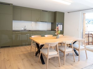 Eine moderne Küche mit grünen Schränken, einem Holztisch und Stühlen.
