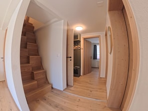 Ein Flur mit Holzdielen, einer Treppe und einer Tür zu einem Badezimmer.