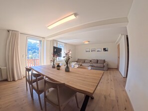 Ein großzügiger Wohnbereich mit einem Holzessttisch, einer Couch und einem an der Wand befestigten Fernseher.