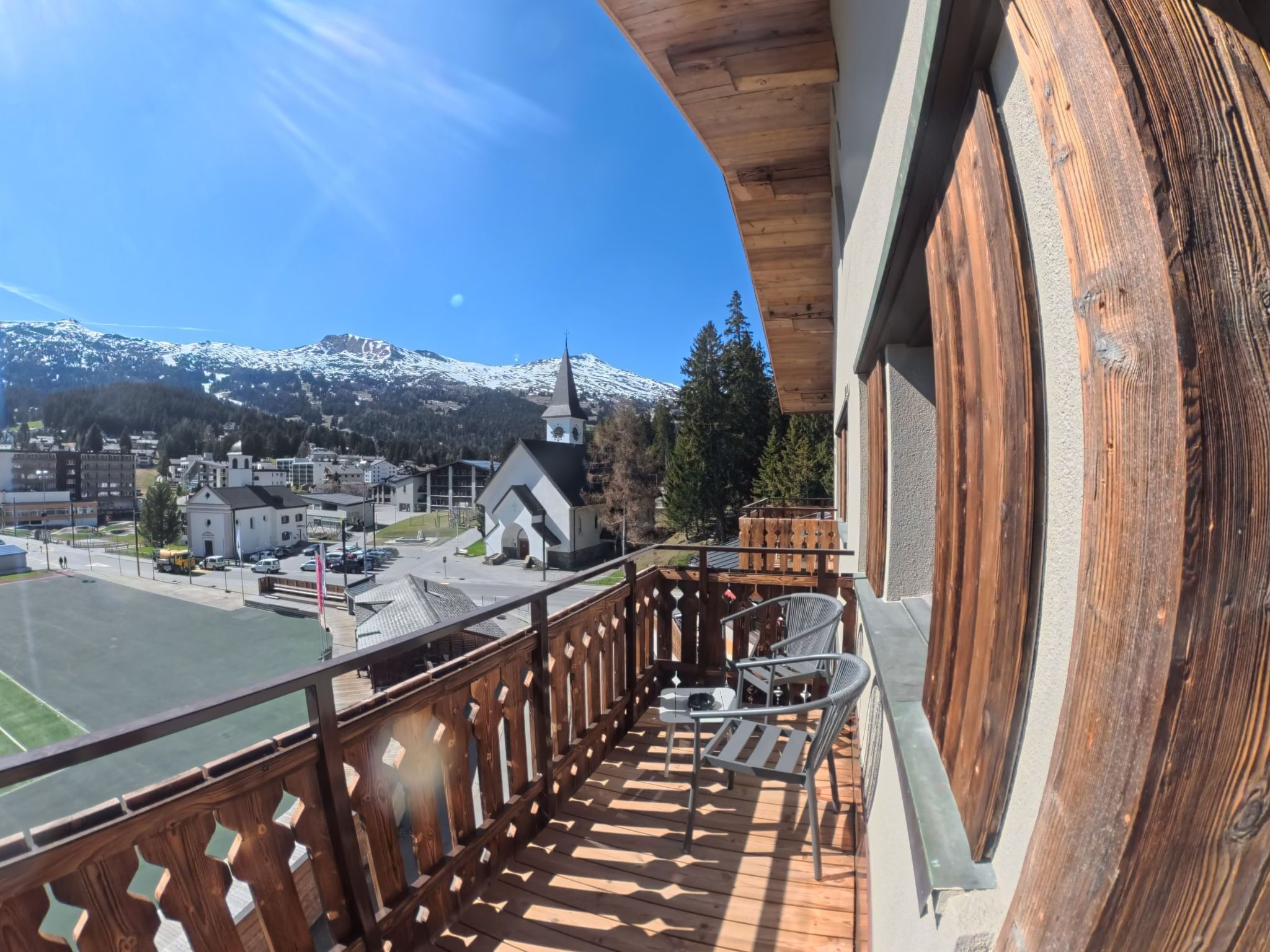 A balcony with a view of a town and snow-capped mountains.