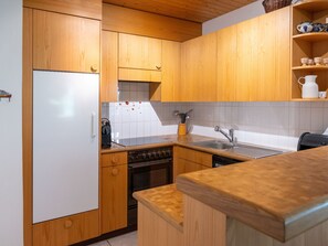 Eine Küche mit Holzschränken, einem weißen Kühlschrank, einem Herd und einem Spülbecken.