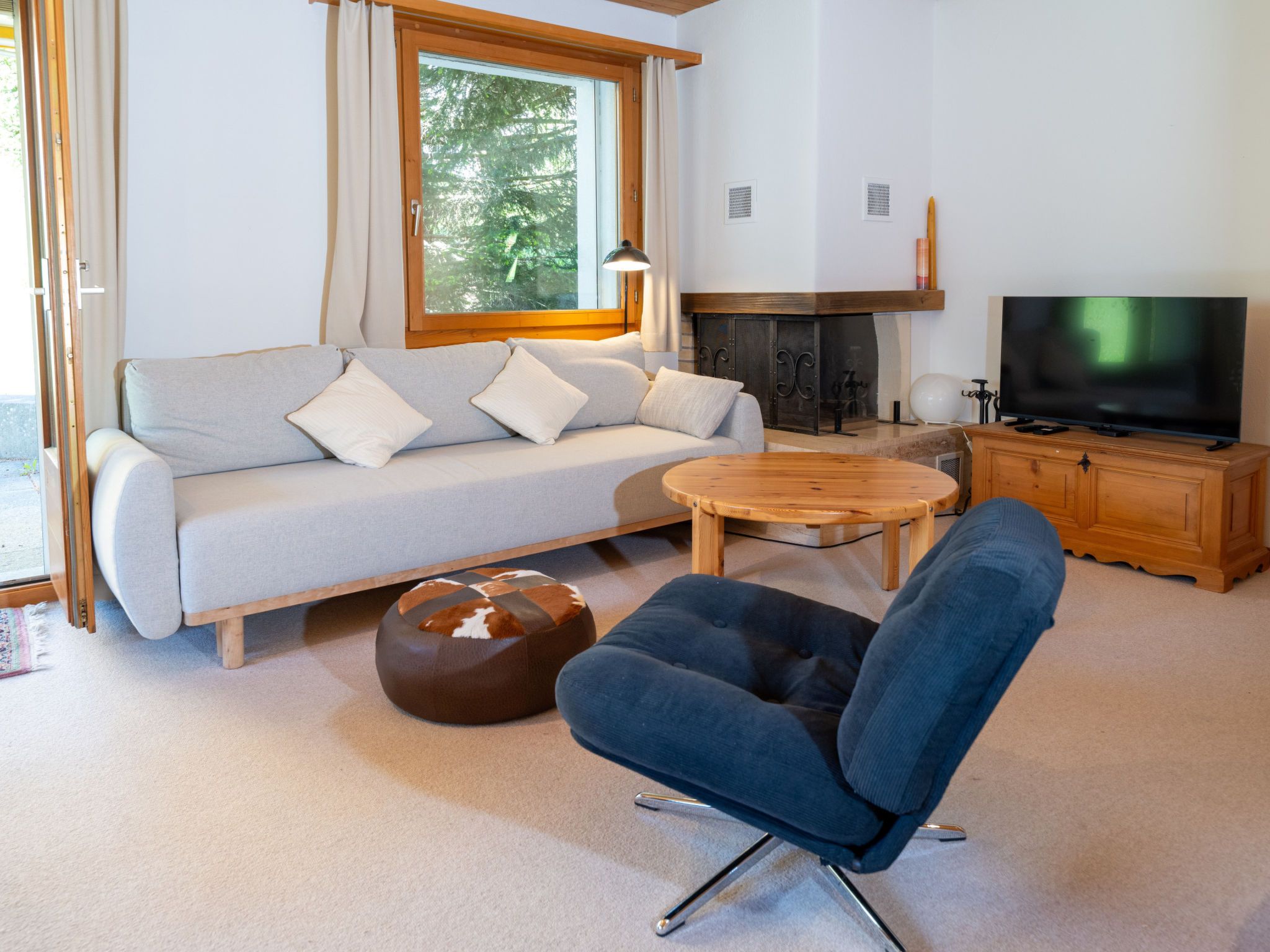 Un salon moderne comprenant un canapé, un pouf, une table basse et un téléviseur.