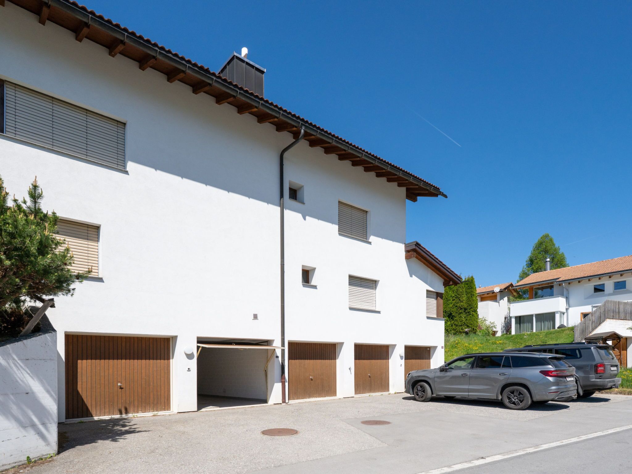 Un bâtiment moderne à deux étages, doté d’un garage, d’une allée et d’un VUS stationné.