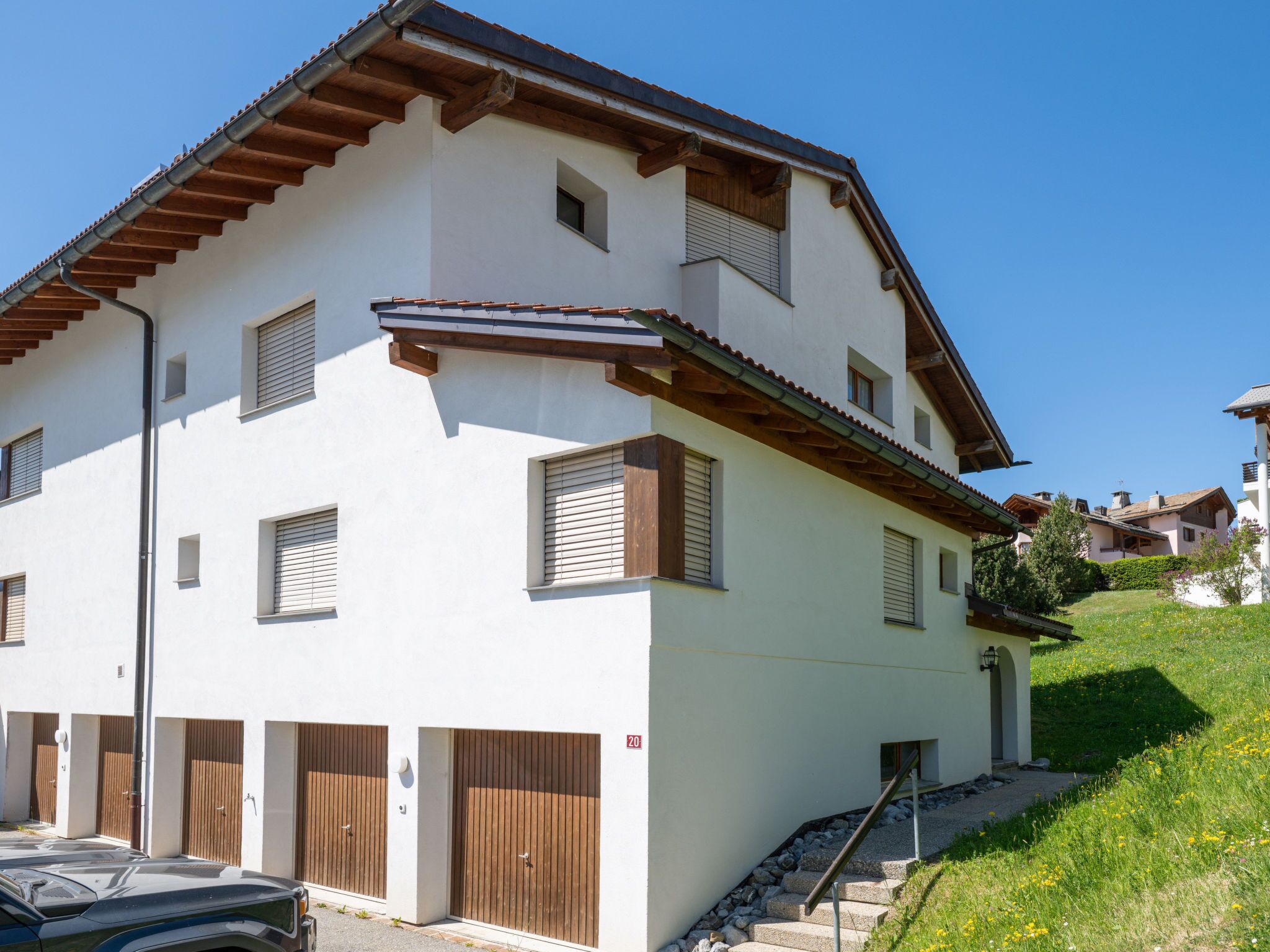 Ein zweistöckiges Gebäude mit weißer Fassade, Holzläden und einem geneigten Dach.