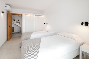 A hotel room with two beds, a wooden door, a staircase, and a white curtain. - Villa in the exclusive Fornells area with beautiful ocean views. Private Pool (Fornells)