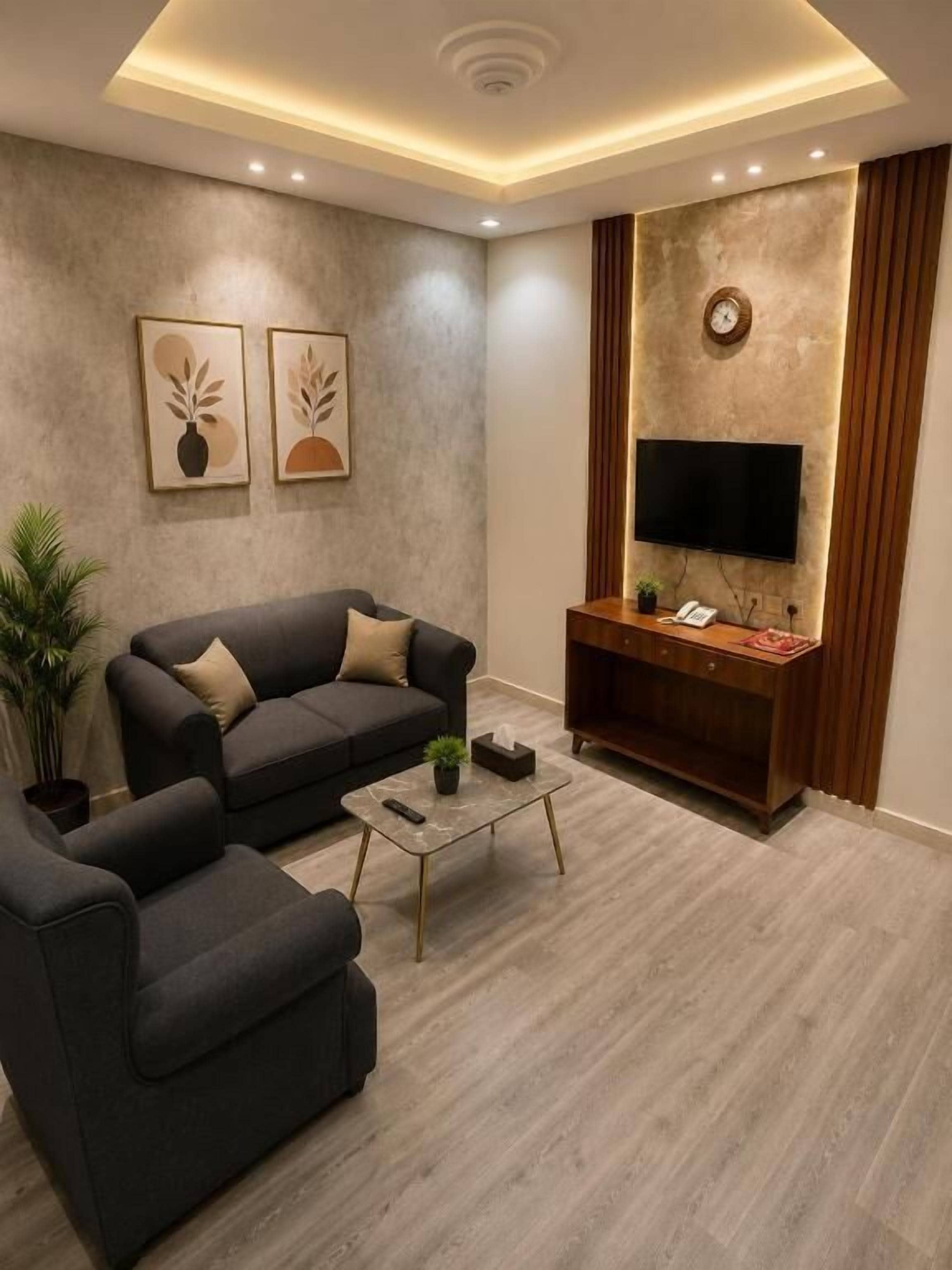 Ein modernes Wohnzimmer mit einer Couch, einem Sessel, einem Couchtisch und einem flachbildfernseher, der an einer strukturierten Wand angebracht ist.