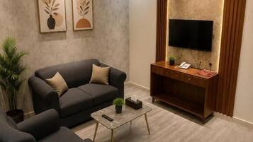 Ein modernes Wohnzimmer mit einer Couch, einem Sessel, einem Couchtisch und einem flachbildfernseher, der an einer strukturierten Wand angebracht ist.