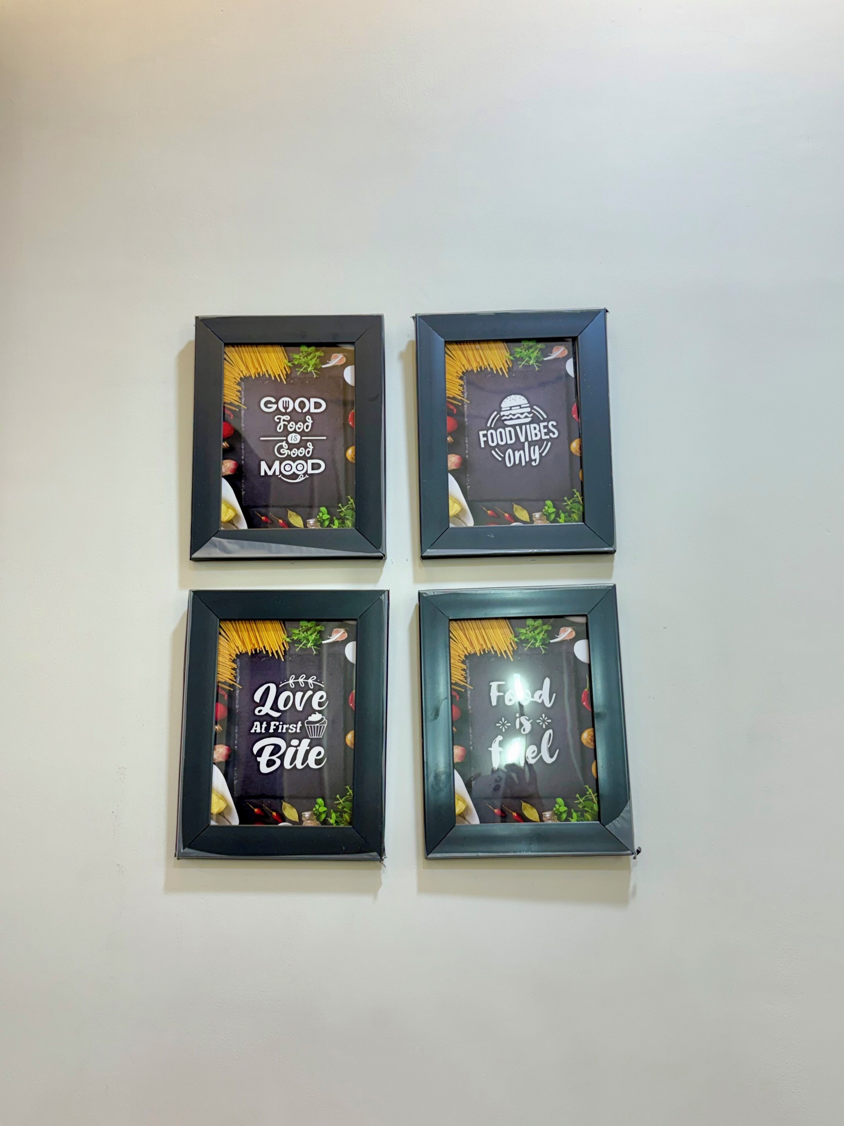 Four framed signs with food-related messages on a wall.