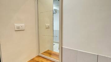 A bathroom with a wooden vanity, a mirror, and a white tiled wall.