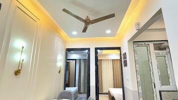 A hotel room with a ceiling fan, a round dining table with two chairs, a bed, and a large mirror.