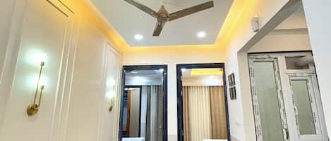 A hotel room with a ceiling fan, a round dining table with two chairs, a bed, and a large mirror.