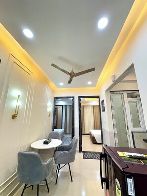 A hotel room with a ceiling fan, a round dining table with two chairs, a bed, and a large mirror.