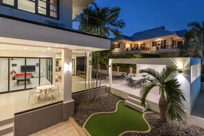 A modern building with a glass-walled office area, outdoor seating, and a rooftop deck. - Spacious 4-bedroom Mansion with indoor pool table near Hua Hin City (Tambon Hua Hin)