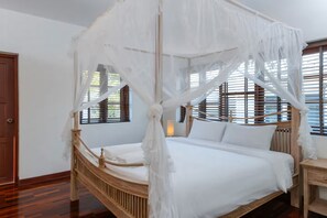 A bed with a canopy, wooden headboard, and bedside table. - Spacious 4-bedroom Mansion with indoor pool table near Hua Hin City (Tambon Hua Hin)