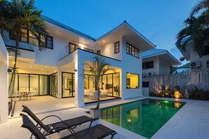 A modern two-story house with a swimming pool, glass doors, and outdoor furniture. - Spacious 4-bedroom Mansion with indoor pool table near Hua Hin City (Tambon Hua Hin)