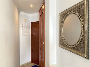 Ein Flur mit einer Holztür, einem Kleiderhaken mit bunten Haken und einem dekorativen Spiegel an der Wand.