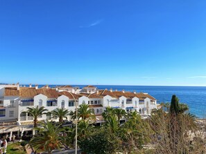 Ein Küstenhotel mit mehreren weißen Gebäuden, einem Strandzugang und Palmen.