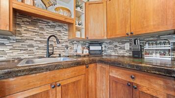 Una cocina con armarios de madera, protector de piedra y encimera de granito.