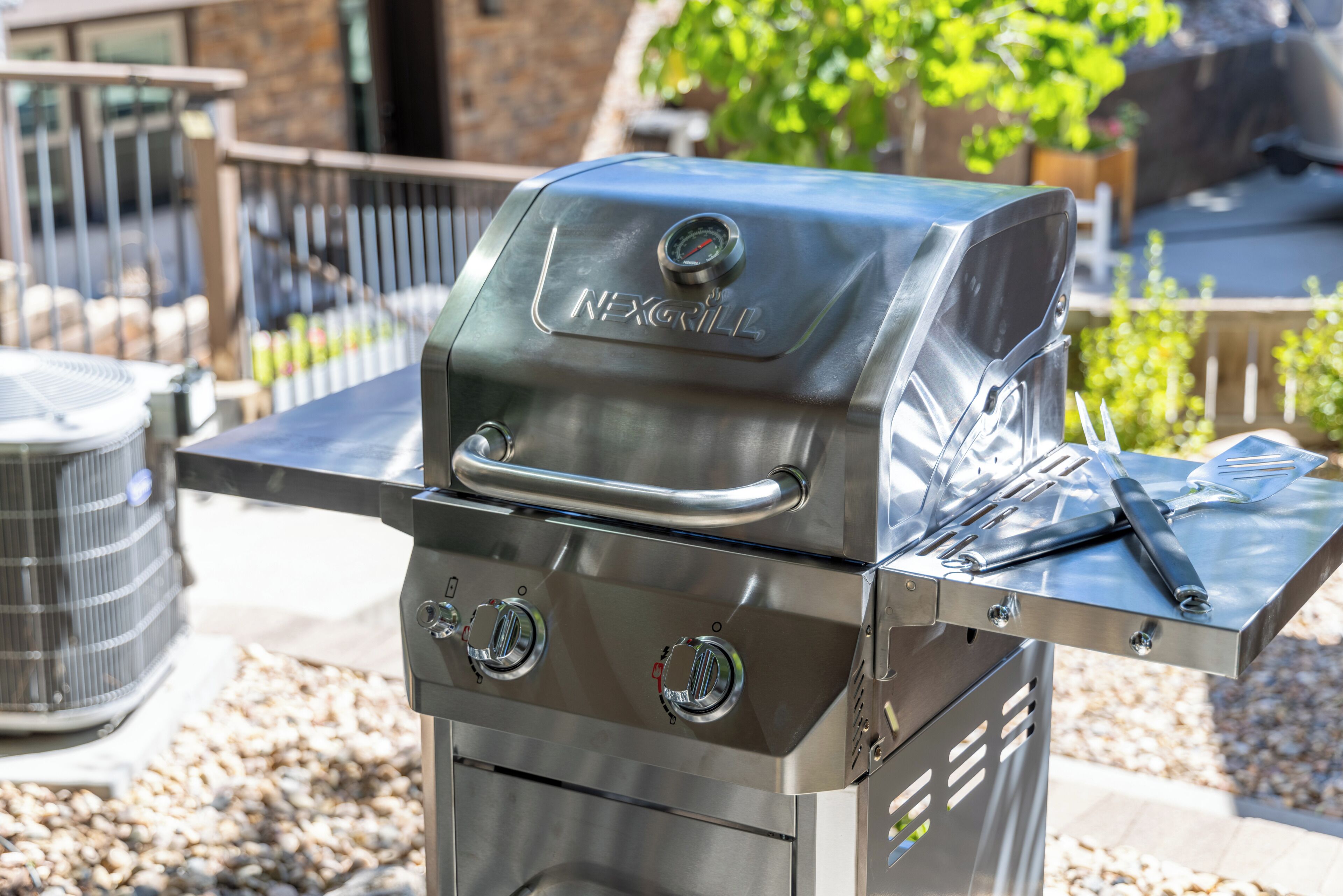 A stainless steel outdoor grill with a digital thermometer and a side burner.