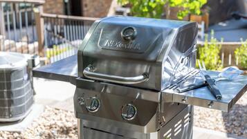 A stainless steel outdoor grill with a digital thermometer and a side burner.