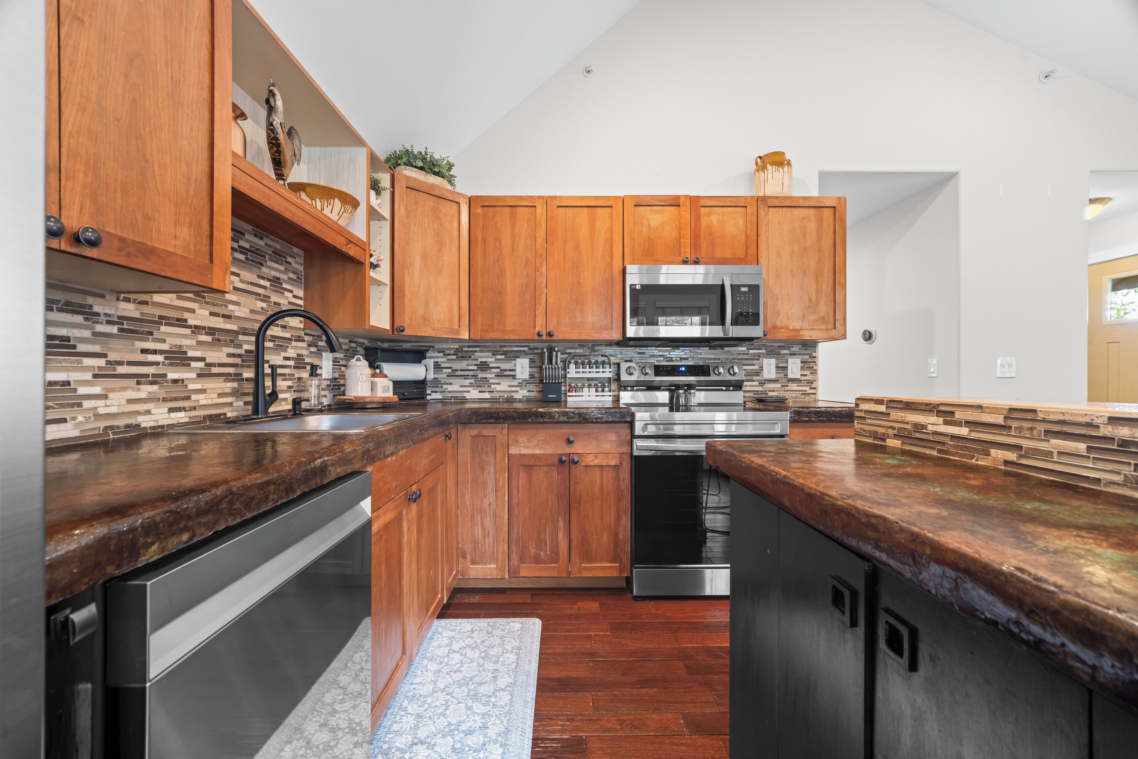 A modern kitchen with wooden cabinets, a stainless steel oven, and a built-in microwave.