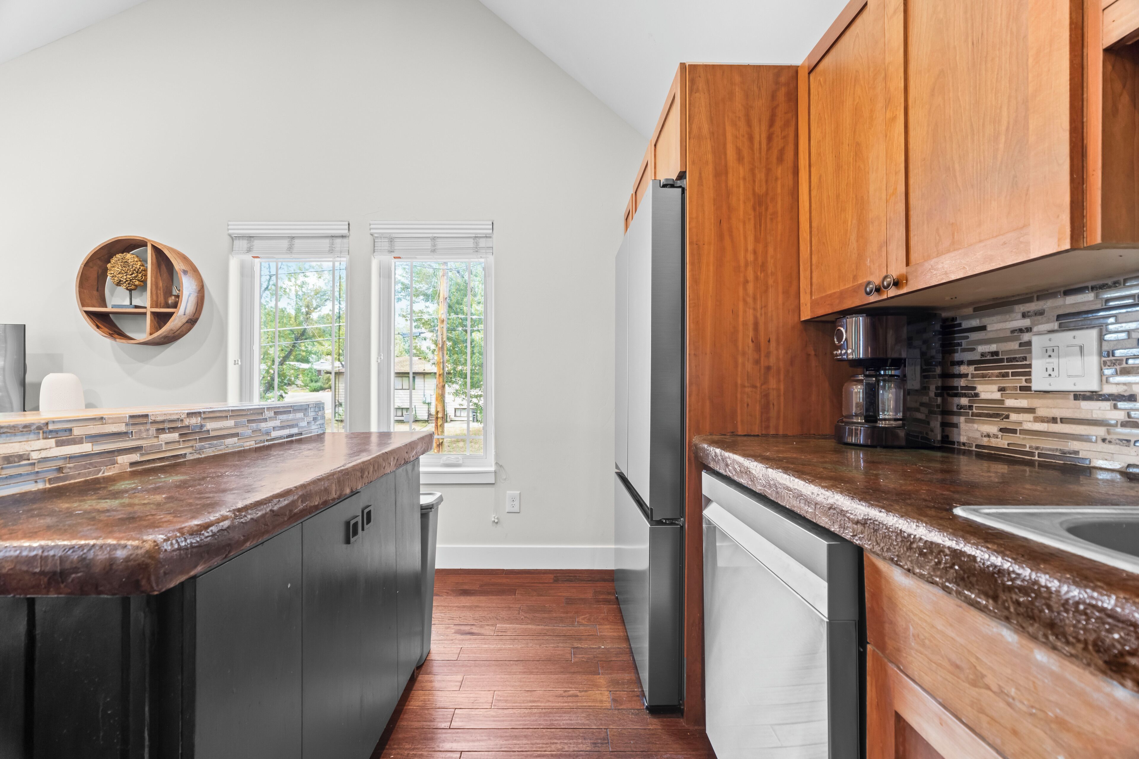 A modern kitchen with wooden cabinets, stainless steel appliances, and a stone backsplash.