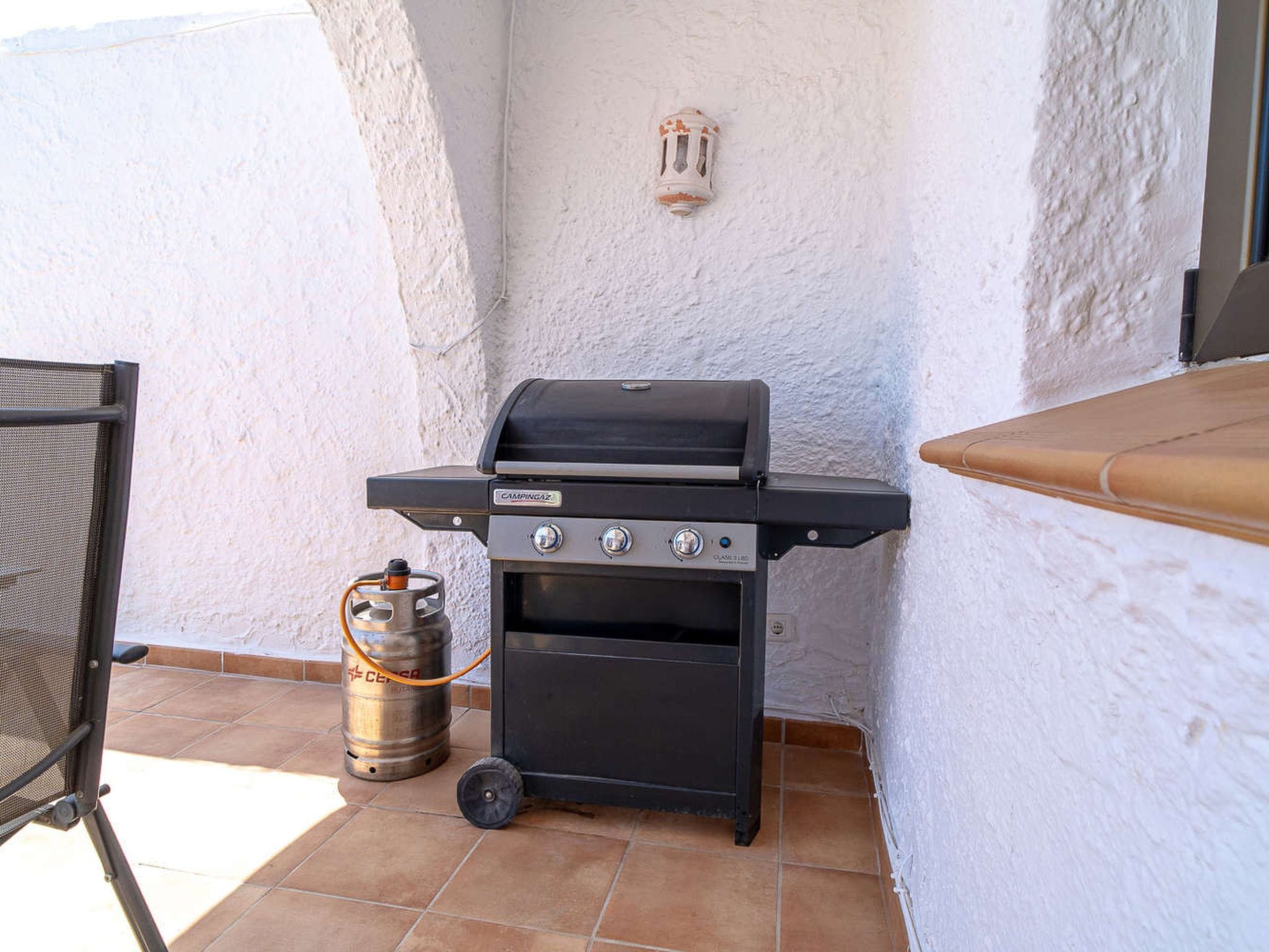 An outdoor grill with a gas tank, a screen, and a control panel.