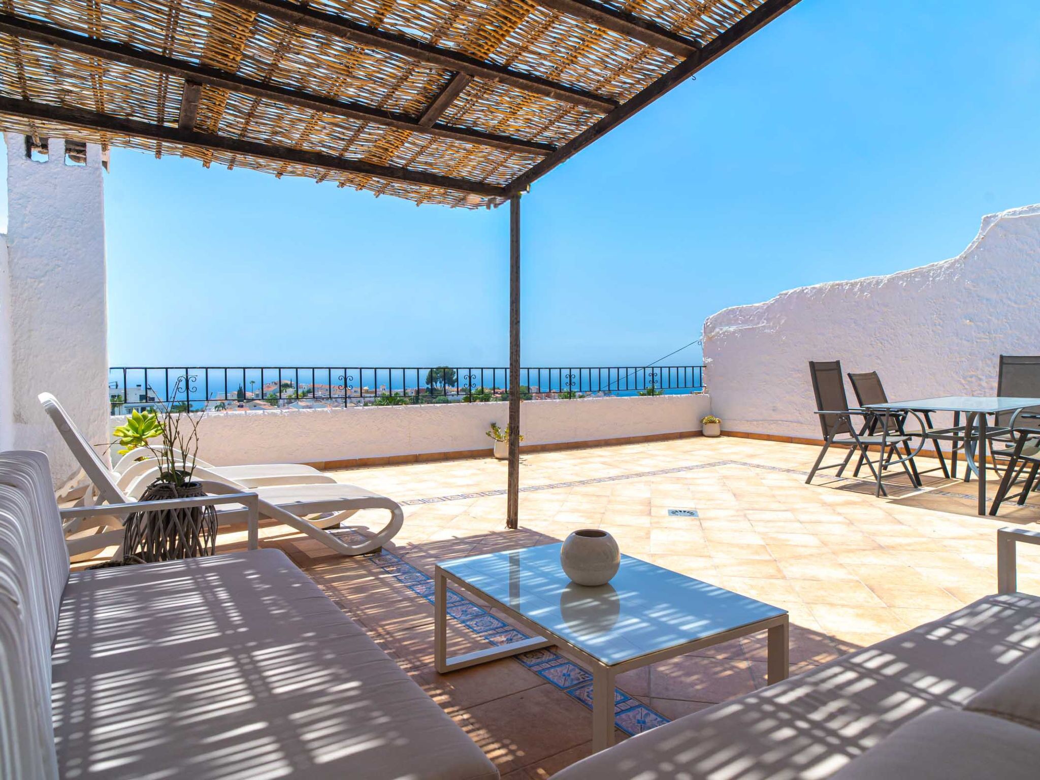 Eine Terrasse mit Meerblick, ausgestattet mit einer Couch, Stühlen und einem Tisch.