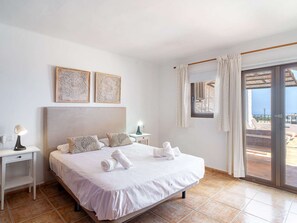 Hotellihuone, jossa on suuri sänky, kaksi yöpöytää, pieni sivupöytä ja liukuovellinen lasiterassi, josta on näkymä ulos.