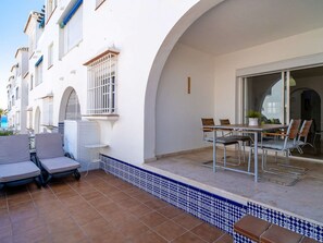 A patio with a table and chairs, a small table with a chair, and a tiled floor. - Las Fuentes Torrecilla by Casasol by Interhome (Nerja)