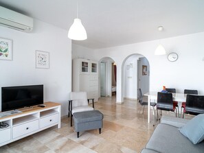A modern living room with a flat-screen TV, a grey sofa, and a dining area with a table and chairs. - Las Fuentes Torrecilla by Casasol by Interhome (Nerja)