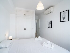 A hotel room with a large bed, a wardrobe, an air conditioning unit, and two framed pictures on the wall. - Apartment  by Interhome (Nerja)